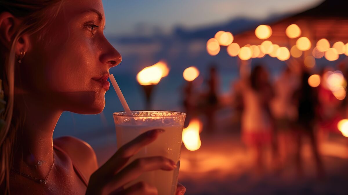 mulher aproveitando um bom drink na praia durante as férias.