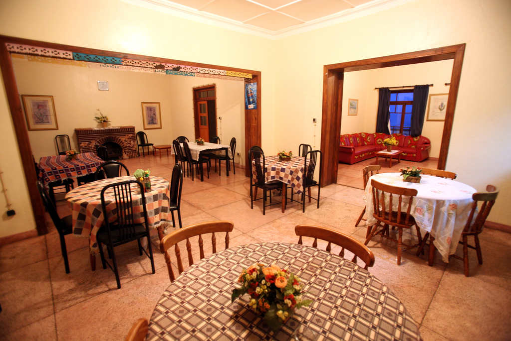 Espaço em uma pousada com mesas decoradas para os hospedes realizarem suas refeições 