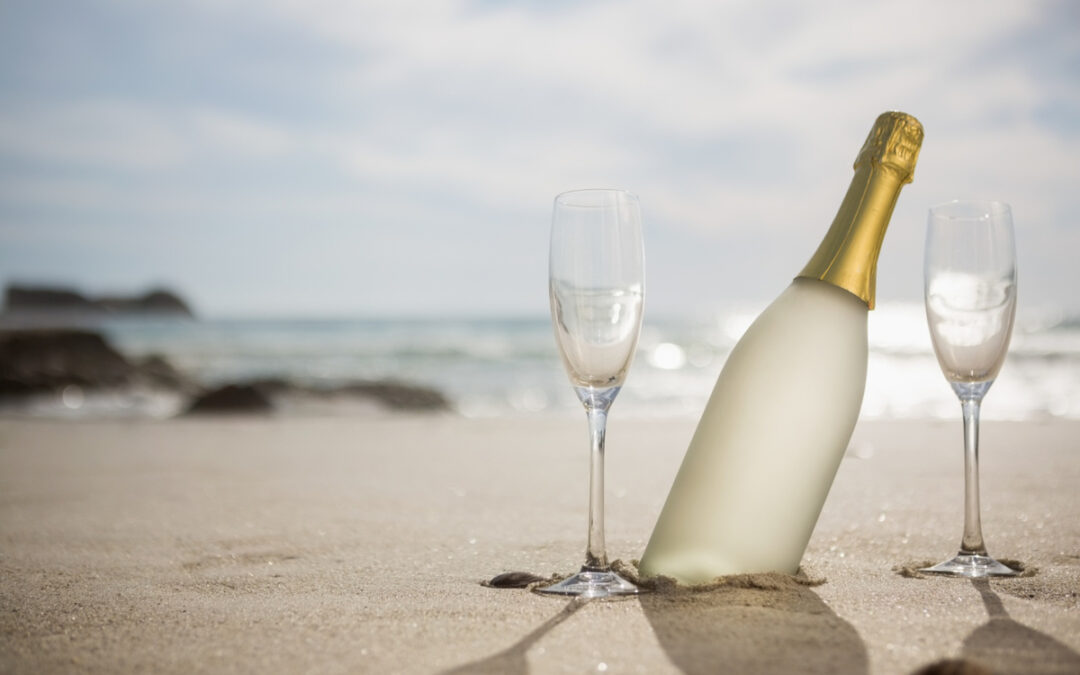 garrafa de champanhe e duas tacas na areia