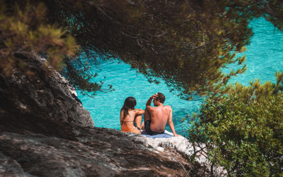 um casal de homens e mulheres conversando em frente a agua turquesa da praia (1)
